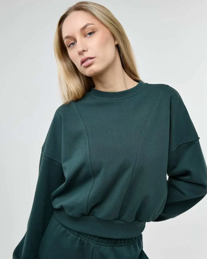 Šviesiaplaukė mergina vilki tamsiai žalią sweatshirt modelio džemperį