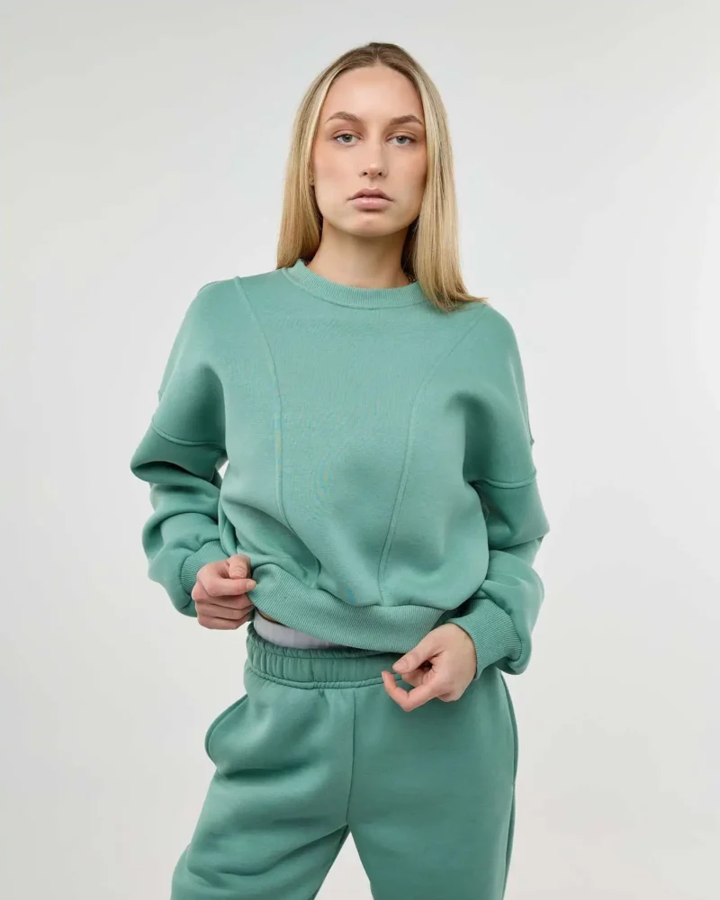 Mergina dėvi šviesiai žalios spalvos sweatshirt džemperį