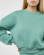 Mergina dėvi šviesiai žalios spalvos sweatshirt džemperį